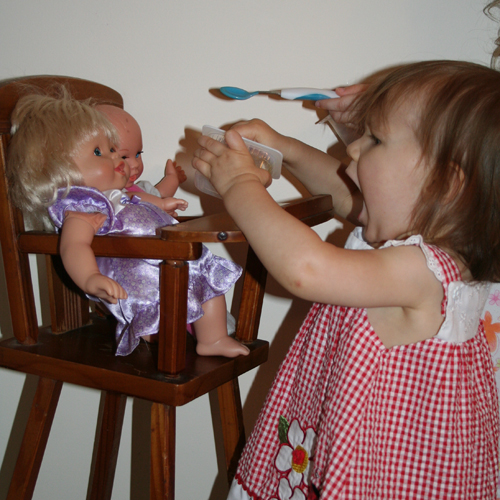 लड़की को गुड़िया खिलाते हुए